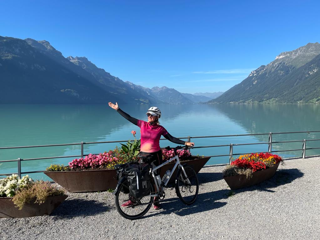 Glückliche Pedalmondo Kundin vor einem schönen See, im Hintergrund Berge, typisch für die Schweiz